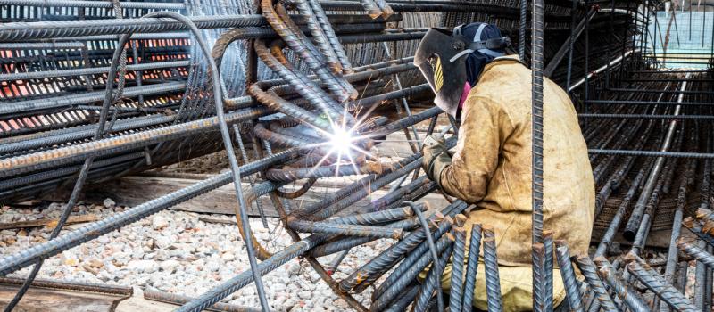 Hombre trabajador del Metro soldando una canastilla de acero