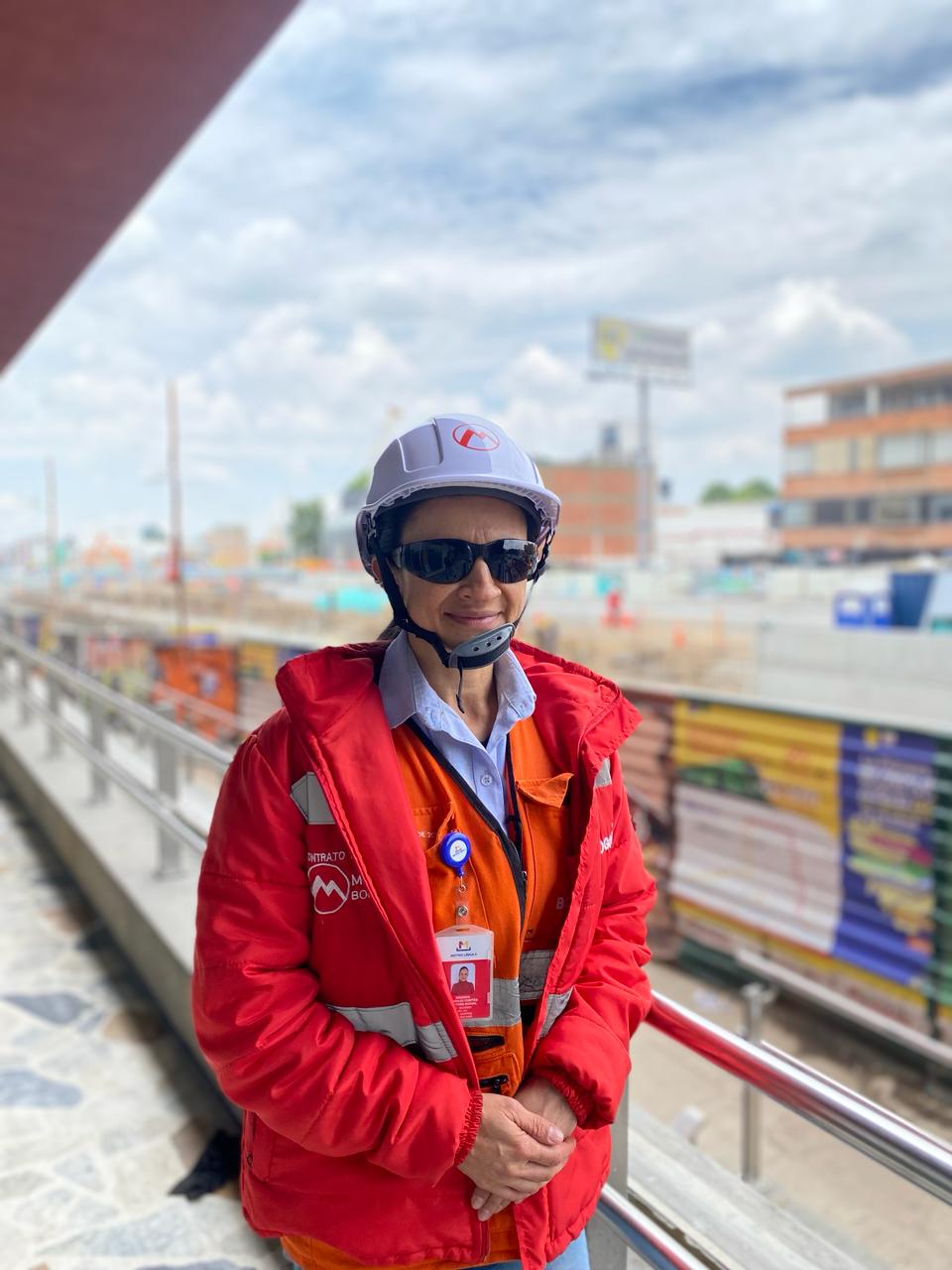 Foto de Amanda sonriendo con su uniforme de trabajo, sonriendo, de fondo la obra de la calle 72
