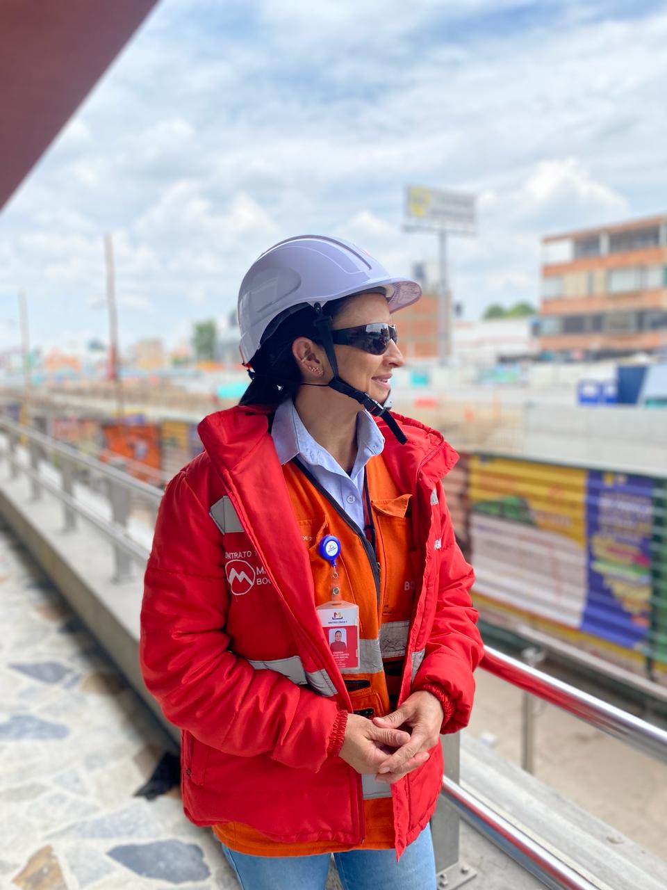 Foto de Amanda sonriendo con su uniforme de trabajo y mirando de lado hacia la obra de la calle 72