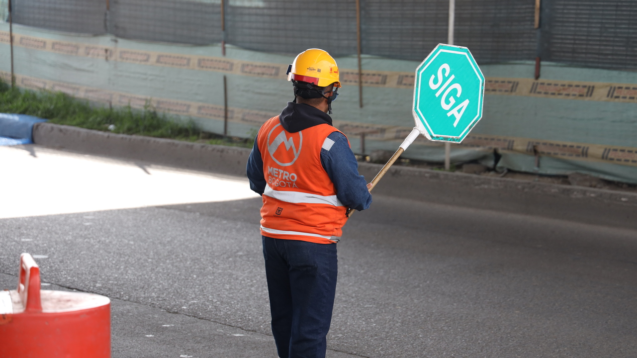 Auxiliar de tráfico sosteniendo una señal de SIGA en la mano derecha