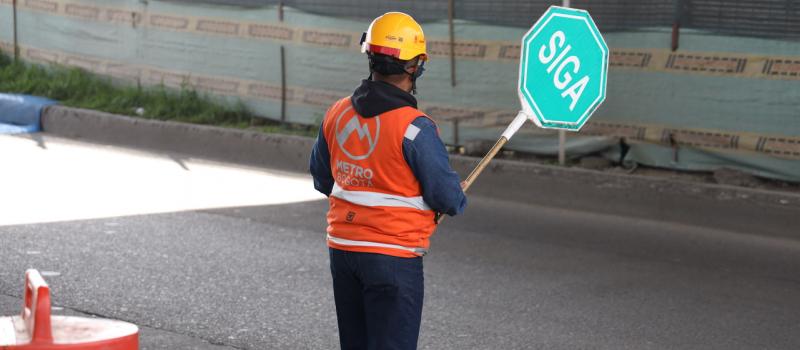 Auxiliar de tráfico sosteniendo una señal de SIGA en la mano derecha