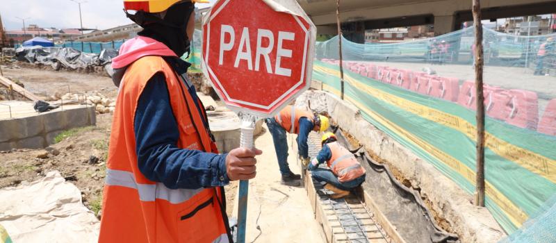 Auxiliar de tráfico en las obras del Metro sosteniendo una señal de PARE